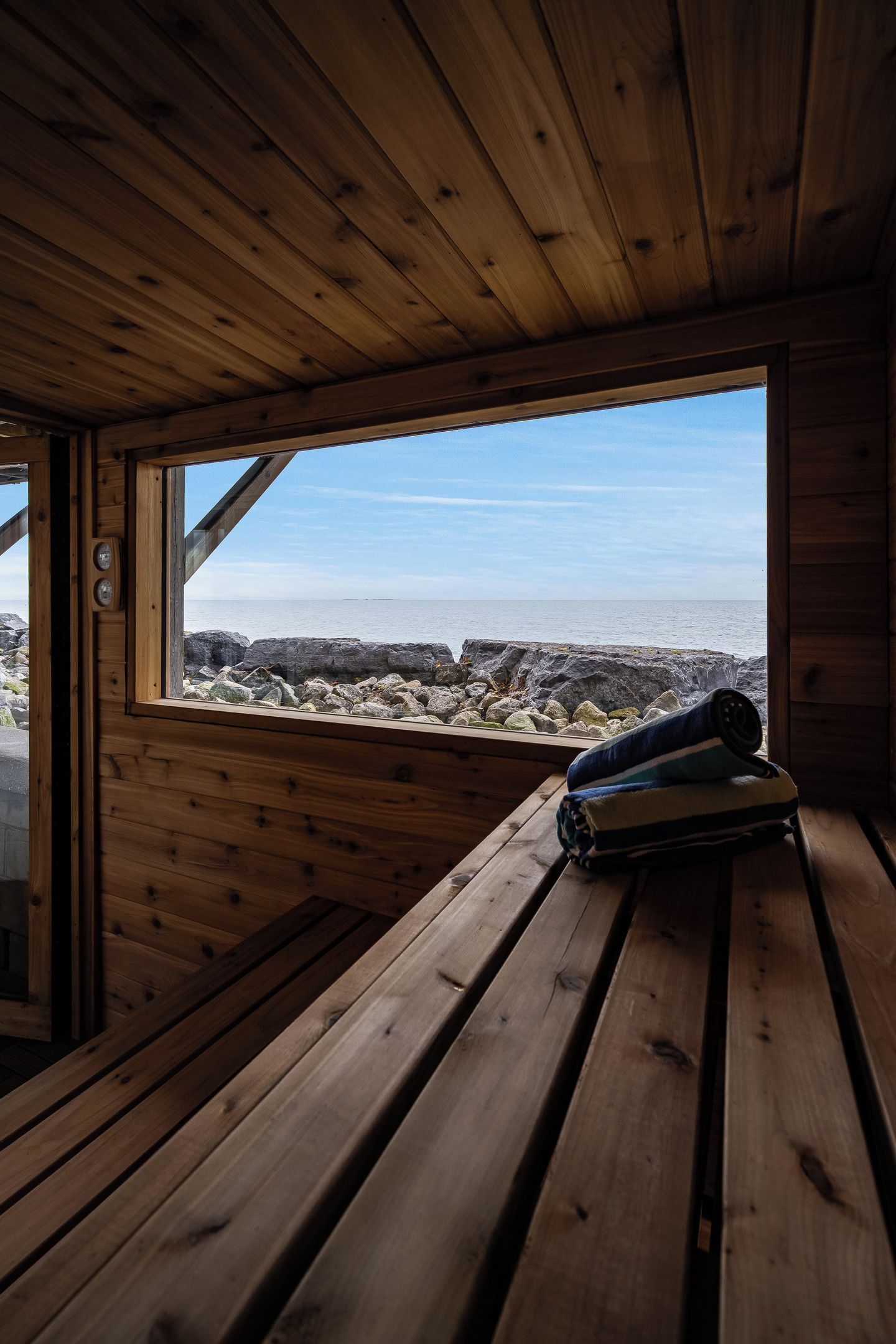 Une cabane en bois avec un banc et une fenêtre donnant sur une côte rocheuse.