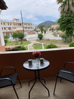 Un balcon avec une table ronde, deux chaises et un vase de fleurs.
