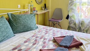 Habitación de hotel con cama, escritorio, silla, espejo y ventana con cortinas.