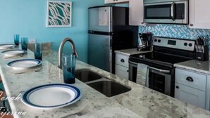 Una cocina con encimera de mármol, electrodomésticos de acero inoxidable y pared azul.