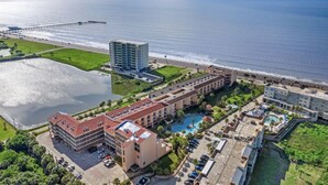 Un hotel frente al mar con varias edificaciones, una piscina y un muelle que se adentra en el océano.