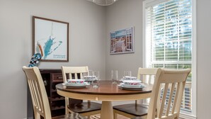 Un coin repas avec une table ronde, quatre chaises et deux tableaux encadrés au mur.