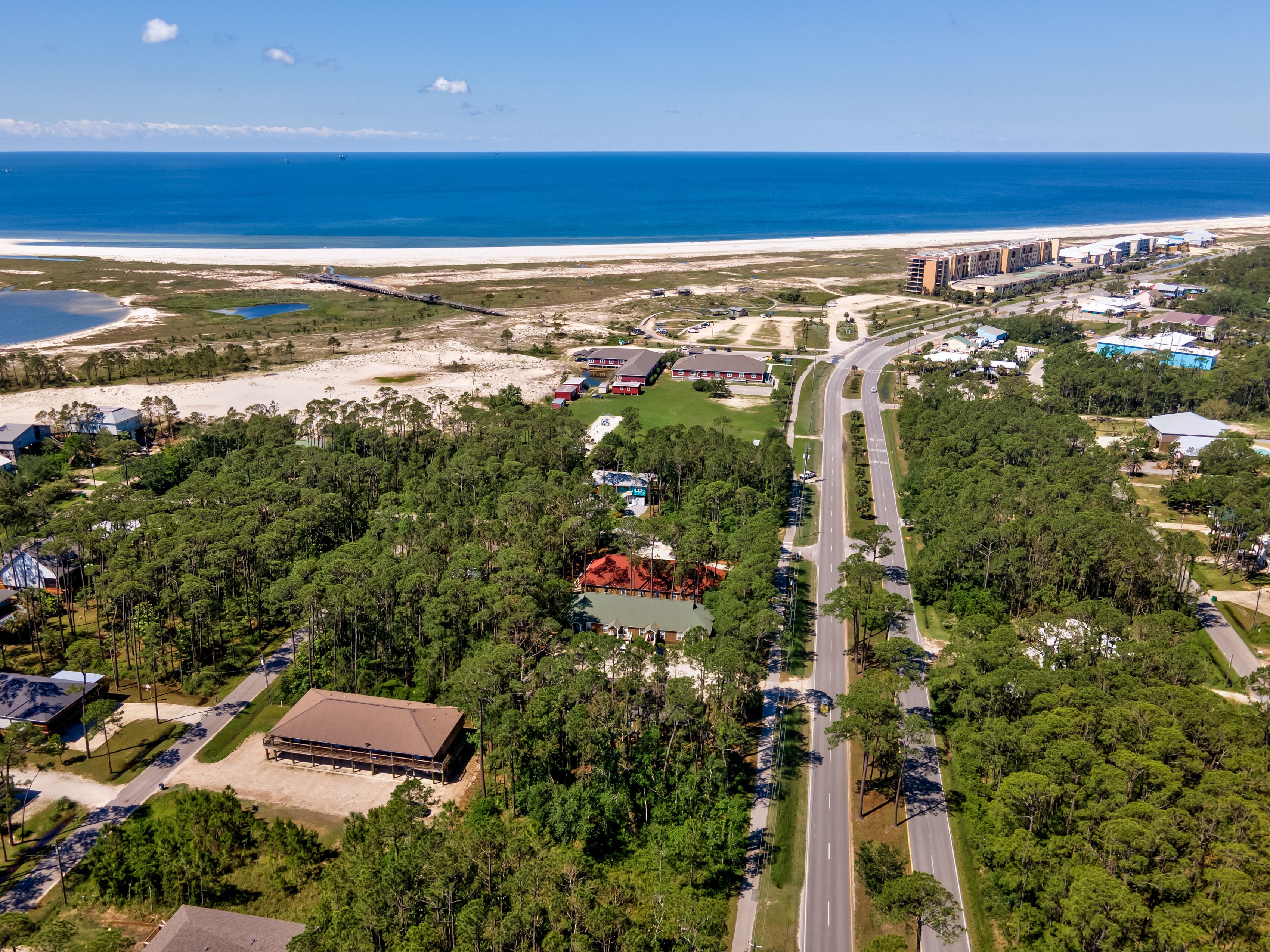 An aerial view of a coastal area with a road, buildings, and a beach.