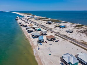 An aerial view of a coastal area with buildings, a road, and a beach.