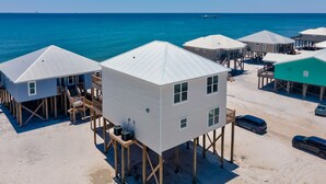 Ein strandnahes Anwesen mit erhöhten Holzgebäuden, jedes mit einem Balkon und einer kleinen Terrasse.