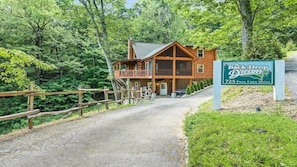 A lodge with a wooden exterior, a porch, and a sign indicating its name and address.