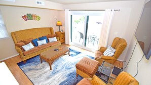 Ein Wohnzimmer mit einer Couch, Sesseln, einem Couchtisch und einem Fernseher.