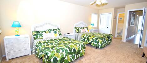 A bedroom with two beds, a ceiling fan, and a nightstand with a lamp.