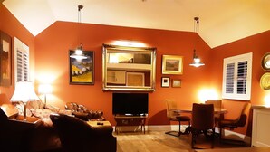 A living room with a sofa, TV, and a dining area with chairs. - Seaside Cottage in Renvyle (Connemara)