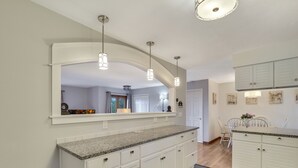 A kitchen with white cabinetry, granite countertops, and pendant lighting. - Beautiful views of Little Traverse Bay and a spacious wraparound deck (Petoskey)