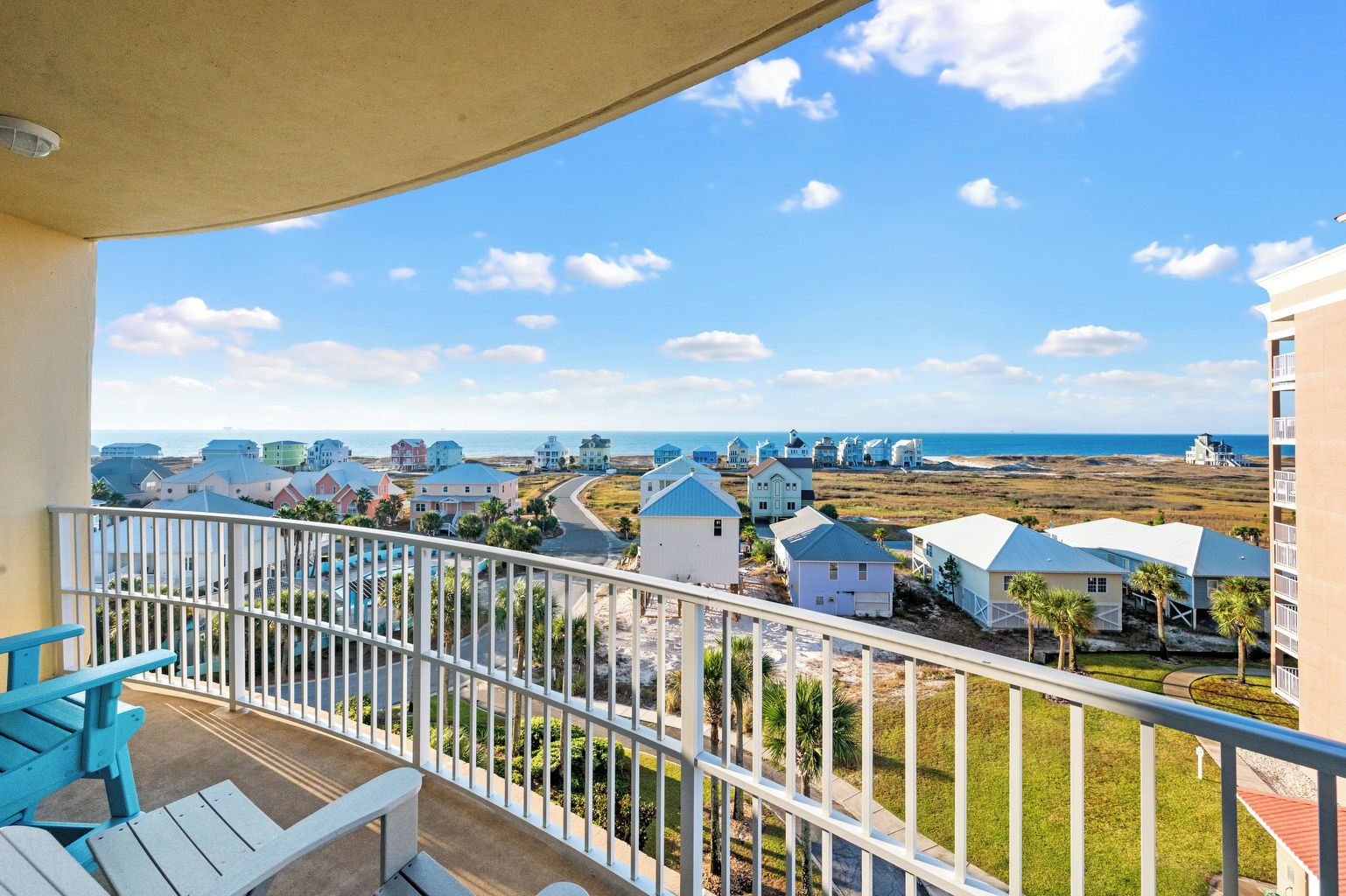 Un balcon donnant sur un quartier résidentiel situé sur la côte, avec vue sur des maisons et une plage.