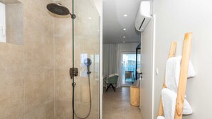 Ein modernes Badezimmer mit einer Glaskabine zur Dusche, einem hölzernen Handtuchhalter und Blick auf den Balkon.