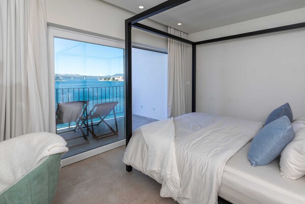 Una habitación de hotel con cama, una silla y vista al mar.