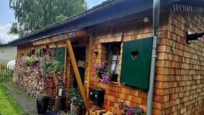 Ein rustikales Holzhaus mit geneigtem Dach, Holzhörnchen und Blumenkästen.