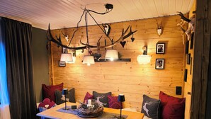 Ein gemütliches Zimmer mit einer Holzwand, einem Tisch mit dekorativer Dekoration und einer Decke mit Geweih-Verzierungen.