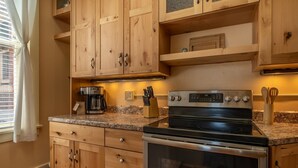 A kitchen with wooden cabinets, a stainless steel stove, and a granite countertop.