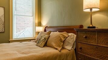 A neatly made bed with a wooden headboard, a bedside lamp, and a dresser with drawers.