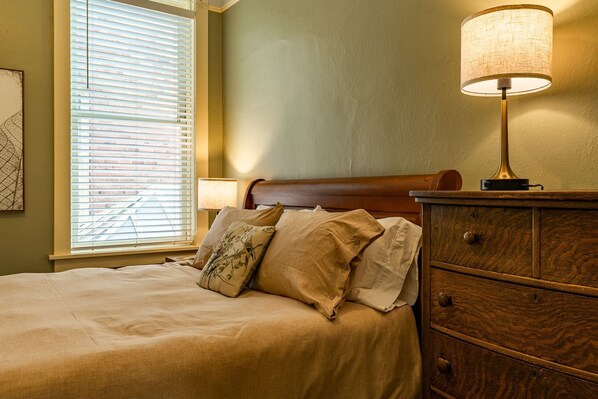 A neatly made bed with a wooden headboard, a bedside lamp, and a dresser with drawers.
