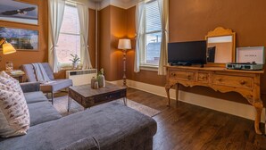 A living room with a sofa, coffee table, TV, and a wooden dresser.