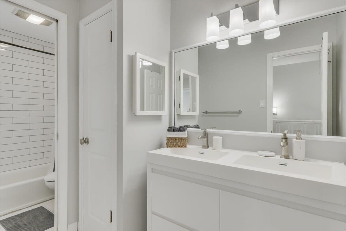 A modern bathroom with a white vanity, a large mirror, and a towel rack.