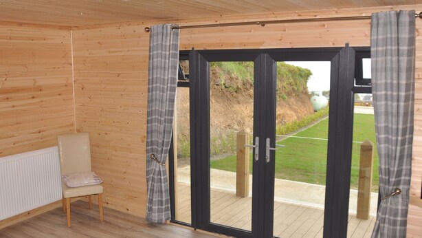 A room with a wooden floor, a white radiator, a bench, and a sliding glass door with curtains.