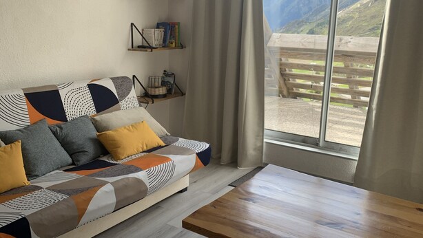 A modern living room with a sofa, wooden table, and a view of mountains through large windows. - Studio cabin Piau Engaly, at the foot of the slopes (Piau-Engaly)