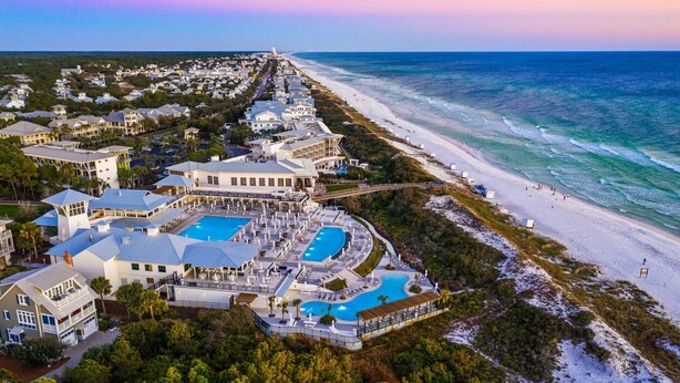 An aerial view of a resort with multiple buildings, a large pool area, and a beach.