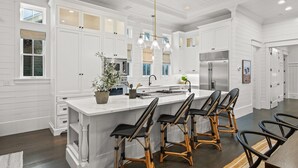 A spacious kitchen with white cabinetry, a large island with bar stools, and modern appliances.