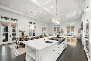A spacious kitchen with a large island, white cabinetry, and a dining area with a table and chairs.