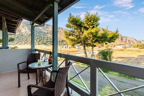 Ein Balkon mit Korbstühlen und einem Tisch, mit Blick auf eine gebirgige Landschaft.
