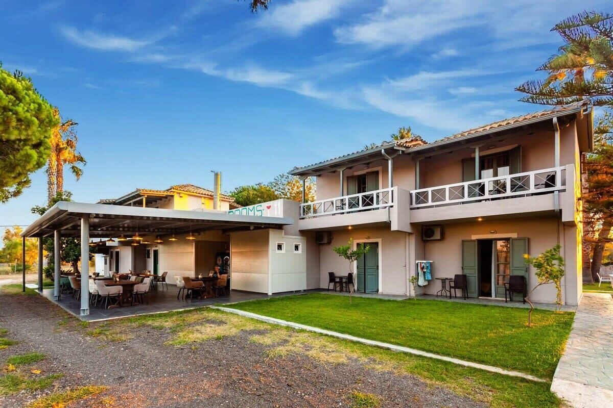 A two-story building with a covered patio area, outdoor seating, and a small garden.