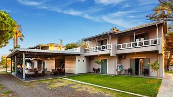 A two-story building with a covered patio area, outdoor seating, and a small garden.