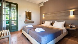 Une chambre d’hôtel avec deux lits, un banc, un miroir et un luminaire fixé au mur.