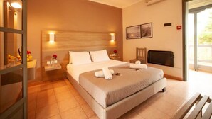 A hotel room with a large bed, bedside tables, a TV, and a sliding glass door to the outside.