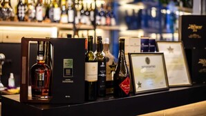 A bar area with various bottles of alcohol, a framed certificate, and a wooden display stand.
