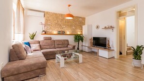 A modern living room with a sectional sofa, a glass coffee table, a flat-screen TV, and a stone accent wall.