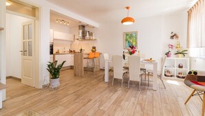 A modern kitchen with white cabinets, a dining area with white chairs, and a bright pendant light.