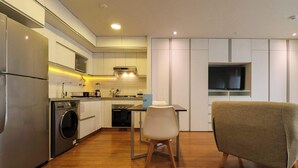 A modern kitchen with built-in appliances, a dining area with a table and chairs, and a TV mounted on the wall.