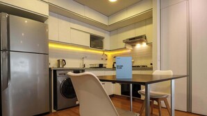 A modern kitchen with stainless steel appliances, a washing machine, and a dining area with a table and chairs.