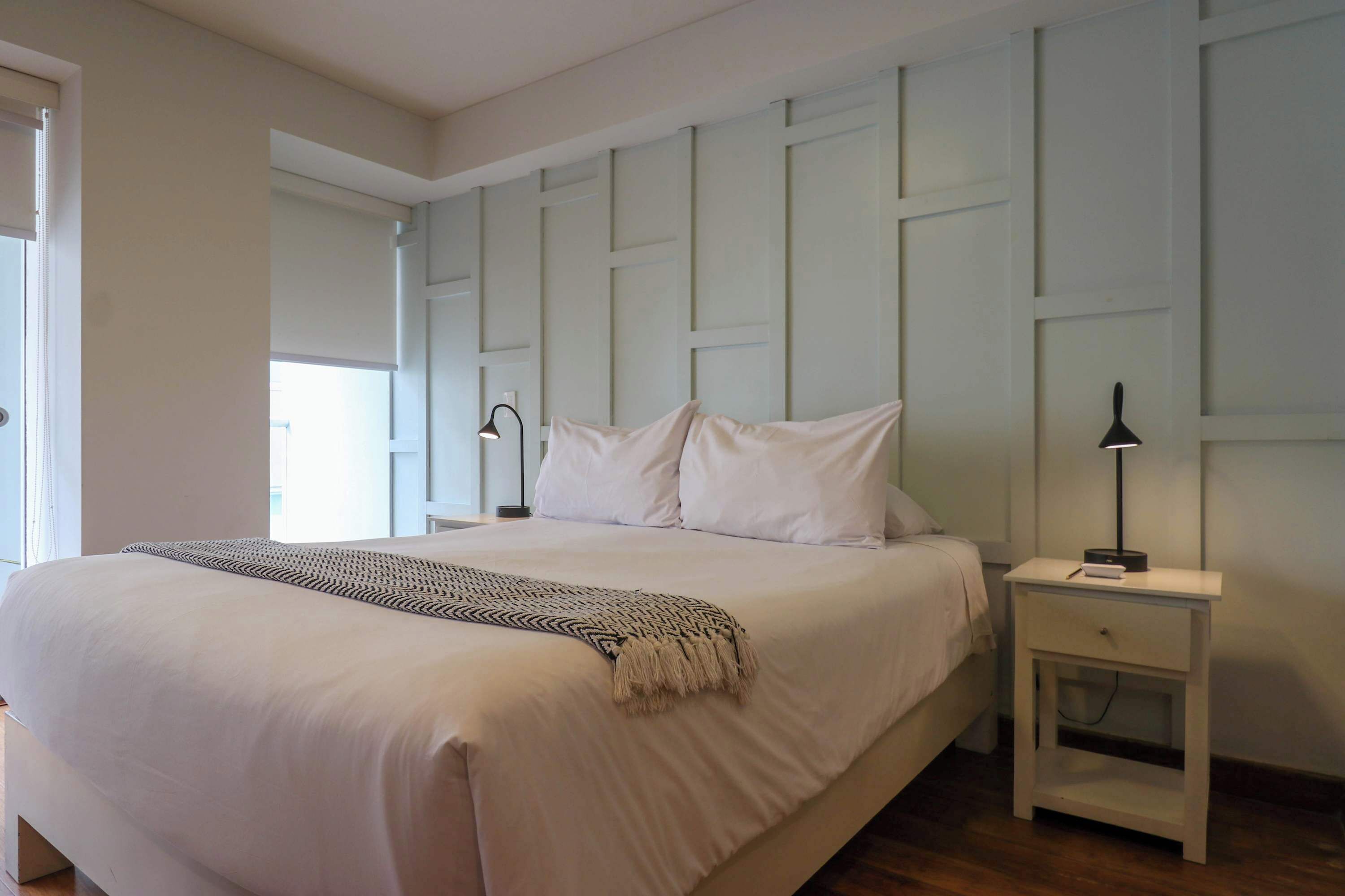 A bedroom with a bed, bedside tables, and a window.