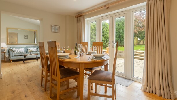 A dining area with a round wooden table set for four, surrounded by wooden chairs. - The Sidings, Docking, Norfolk (Docking)