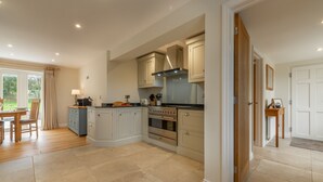 A spacious kitchen with a central island, wooden cabinets, and a large oven. - The Sidings, Docking, Norfolk (Docking)