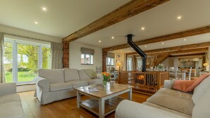 A spacious living room with a wooden ceiling, a large window, and a view of the outdoors. - The Big Barn, Snettisham, Norfolk (Snettisham)