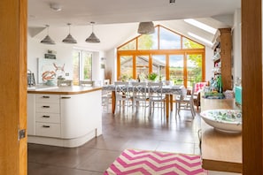 A modern kitchen with a large island, white cabinetry, and a dining area with a table and chairs.