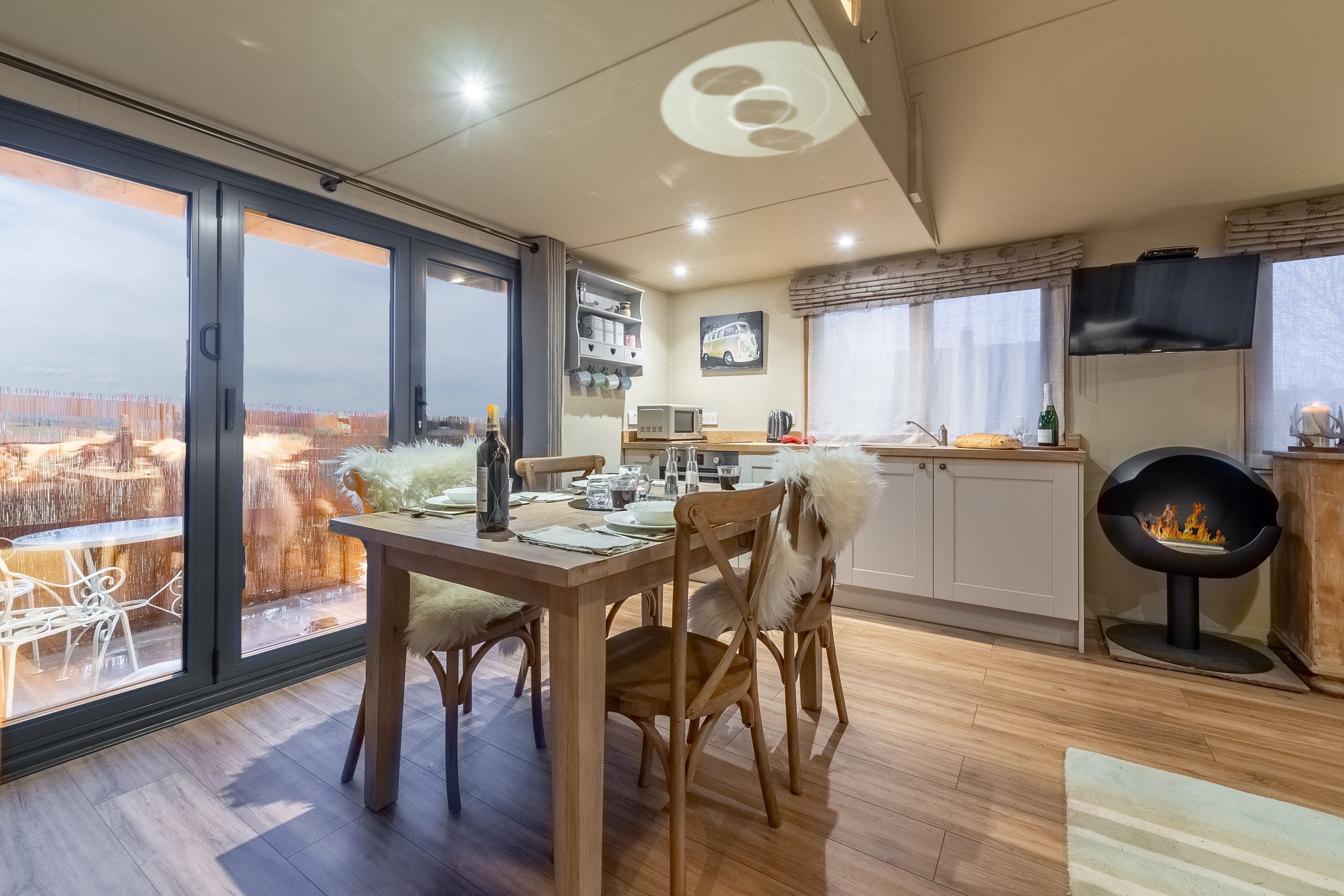 A dining area with a view, a fireplace, and a kitchen with a TV.