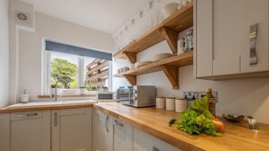 Cozinha moderna com bancadas de madeira, prateleiras embutidas e vista para o verde lá fora.