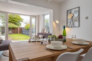 Enjoy meals in this dining area with a view of the backyard, featuring a table, framed artwork, and a large window.