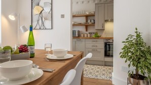 Uma cozinha moderna com armários brancos, bancada de madeira e um vaso com planta.