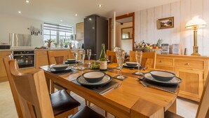 Cozinha moderna com armários de madeira, mesa de jantar posta para seis pessoas e uma janela grande que oferece luz natural.