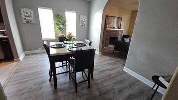 A dining area with a table set for four, a fireplace, and a staircase leading to another level.